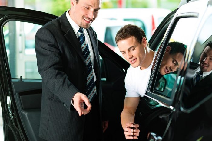 Young man and sales agent checking a car