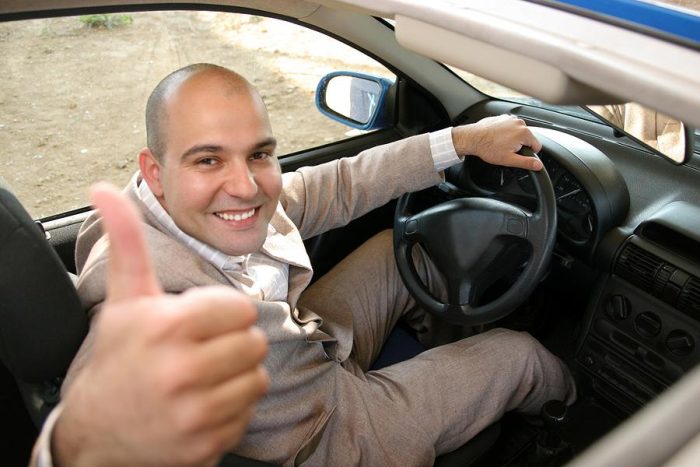 Happy young man doing a test-drive of a used car