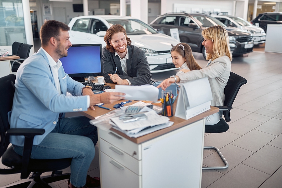 Salesman and family at car dealership