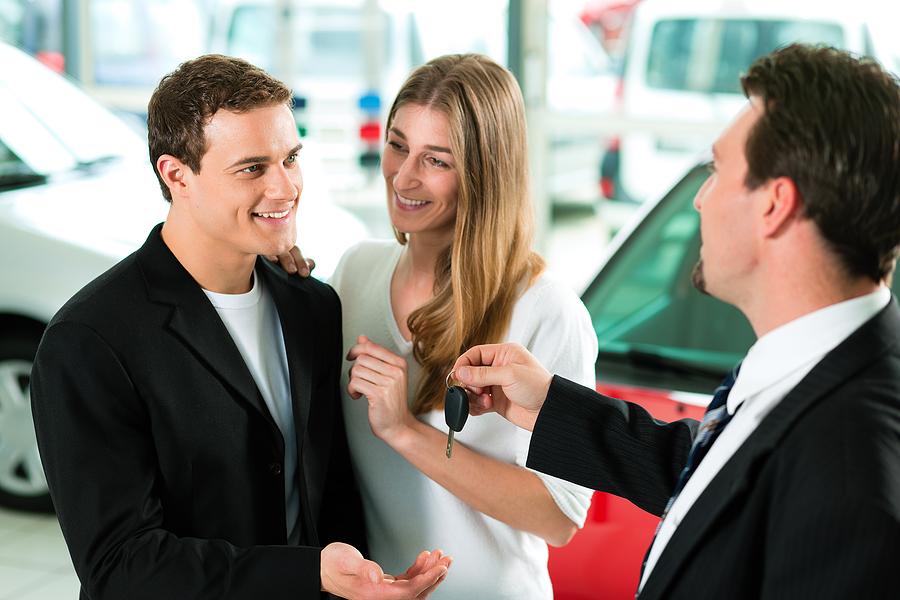 Happy couple talking to a car dealership agent