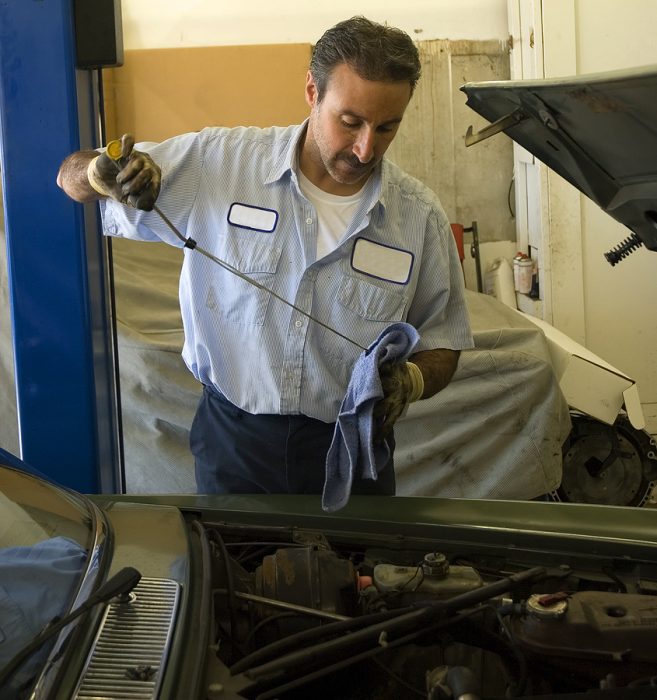 a mechanic checks the oil on a car being repaired