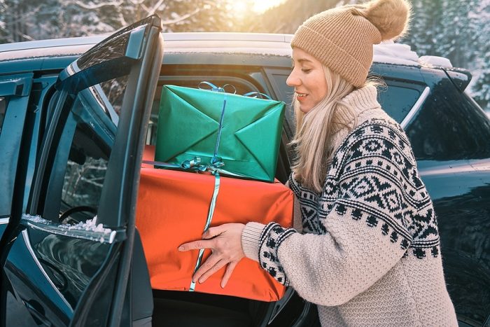 Woman Giving Gifts. Woman holding presents and delivering them on her car.